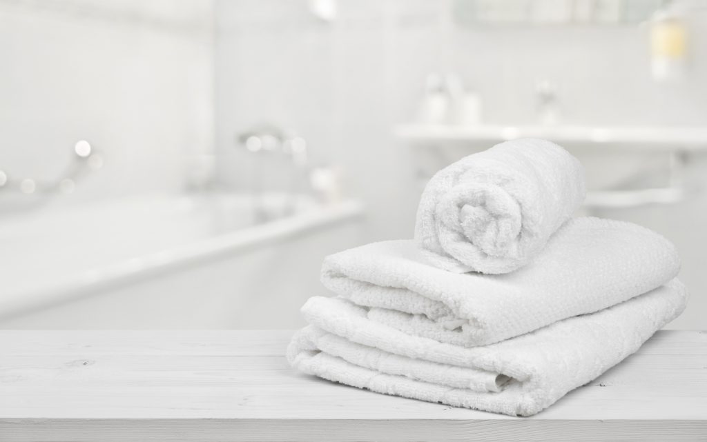 Stack of folded white spa towels over blurred bathroom background