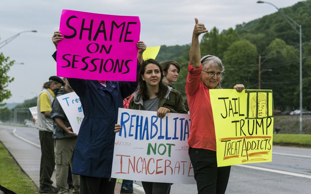 Protestors hold up signs as they await the arrival of Attorney General Jeff Sessions, who gave opening remarks during a Drug Enforcement Administration (DEA) 360 Heroin and Opioid Response Summit at the University of Charleston, Thursday, May 11, 2017, in Charleston, W.Va. The event, which was sponsored by the DEA, Community Anti-Drug Coalitions of America and the University of Charleston School of Pharmacy, was held to provide solutions and strategies for combating the heroin and prescription drug abuse epidemic. (AP Photo/Sam Owens)